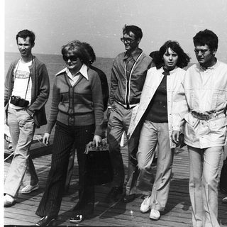Group of people walking outdoors in retro 1970s-80s attire.