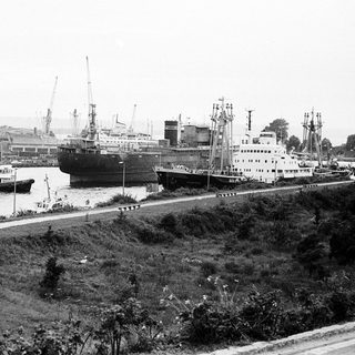 Historic port with docked ships and industrial cranes.