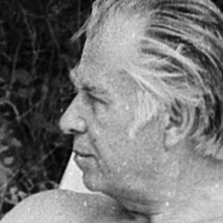 Shirtless man relaxing in folding chair outdoors.