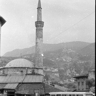 Historic mosque with tall minaret in urban setting.