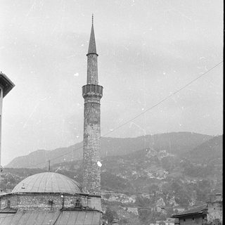 Historic mosque with tall minaret in urban setting.