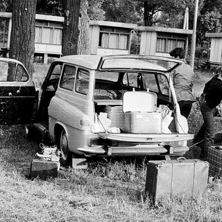 People setting up a tent near parked cars.