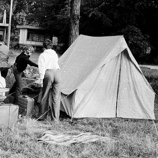People setting up a tent near parked cars.