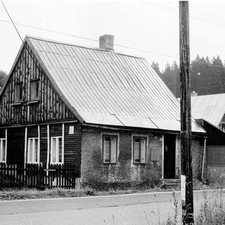 Rural wooden house with sloped roof, black and white.