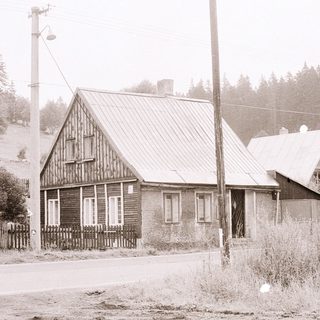 Rural wooden houses on a foggy roadside.