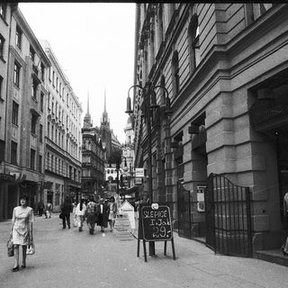 Urban street scene with pedestrians, historic buildings, and signage.