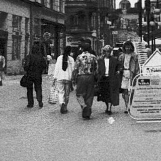 Urban street scene with pedestrians, historic buildings, and signage.