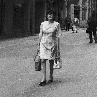 Urban street scene with pedestrians, historic buildings, and signage.