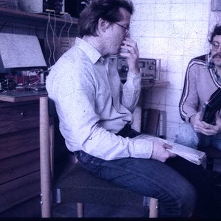 Two men discussing in a retro office workspace.