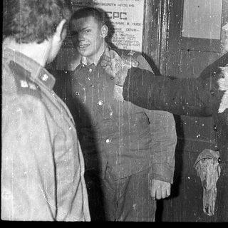 Two men standing near Soviet-era noticeboard.