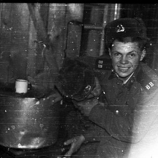 Young soldier in wartime uniform smiling indoors.
