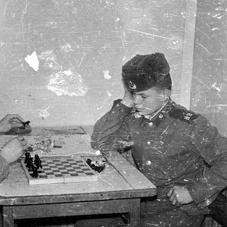 Two soldiers playing chess in a makeshift room.