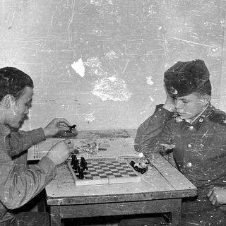 Two soldiers playing chess in a makeshift room.