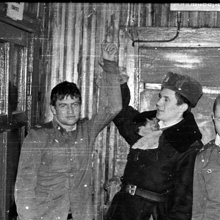Three men in military uniforms pose indoors.