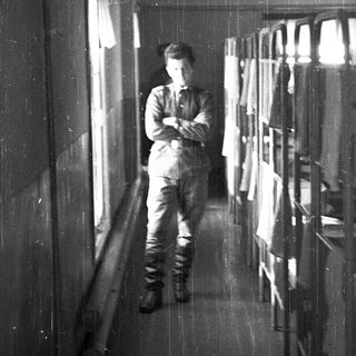 A man in uniform stands alone in a dimly lit hallway.