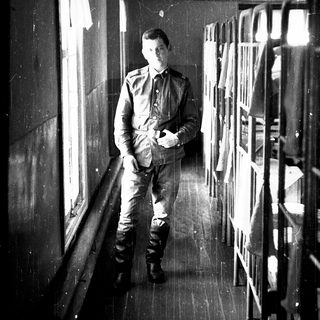 Young man in military uniform standing in train compartment.