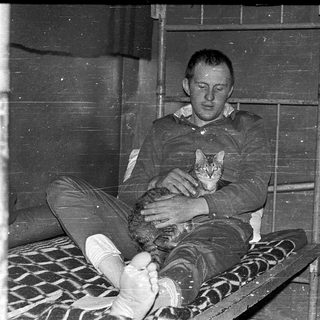 Man holding kitten in makeshift prison bunk.