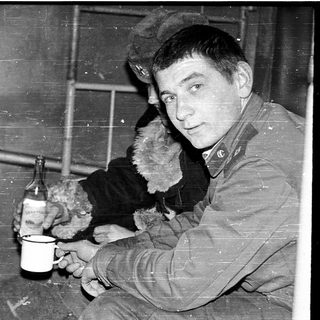 Two men in winter clothing drinking indoors.