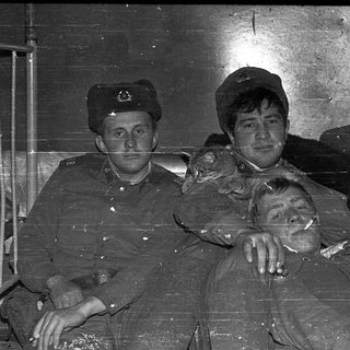 Three men in military uniforms posing indoors.