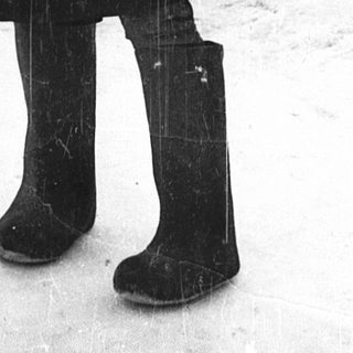 Person in winter military attire standing outdoors in snow.