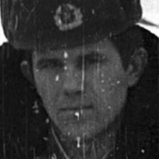Person in winter military attire standing outdoors in snow.