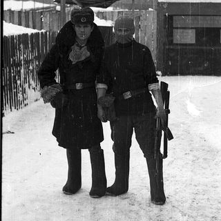 Two soldiers in winter gear standing in snow.