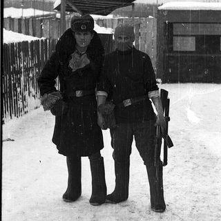 Two soldiers in winter gear standing in snow.