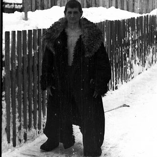 Man dressed in heavy winter coat standing in snowy outdoor setting.