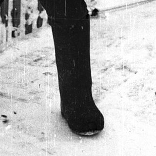 Shirtless boy standing in snowy outdoor setting.