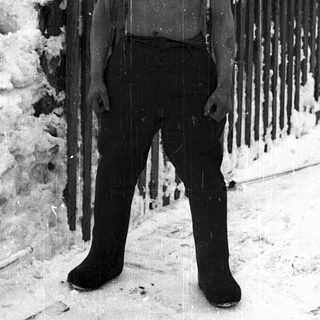 Shirtless boy standing in snowy outdoor setting.