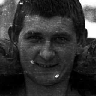 Shivering man wearing fur-lined coat in snow.