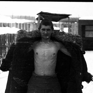 Shivering man wearing fur-lined coat in snow.