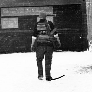 Person in winter uniform walks through snowy courtyard.