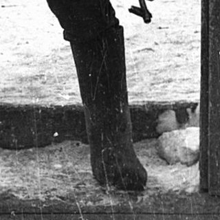 Man in winter gear standing at open gate.