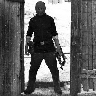 Man in winter gear standing at open gate.