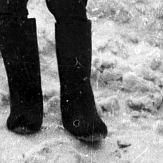 Soldier in winter uniform standing near barbed wire.