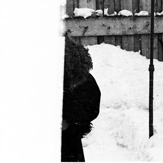 Snow-covered wooden fence with bent poles.