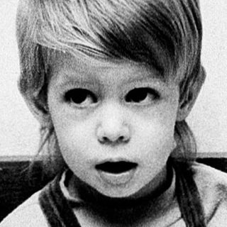 Young child reading book intently indoors.