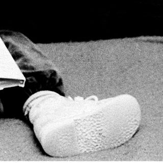 Young child reading book on bed.