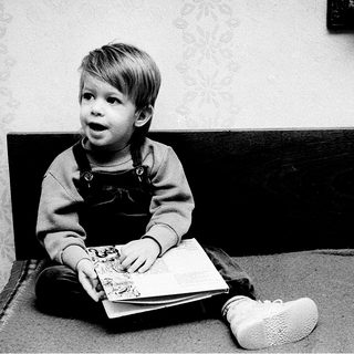 Young child engrossed in reading book.
