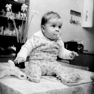 Baby sitting on table with toy.