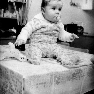 Baby sitting on table with toy.