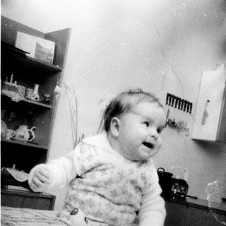 Baby wearing fluffy sweater sitting on table.