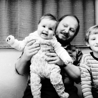 Family portrait with man holding baby, young boy smiling.