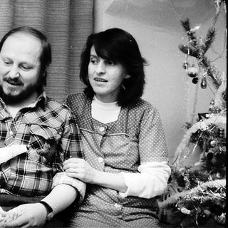 Family portrait with parents and baby near Christmas tree.