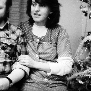 Family portrait with parents and baby near Christmas tree.