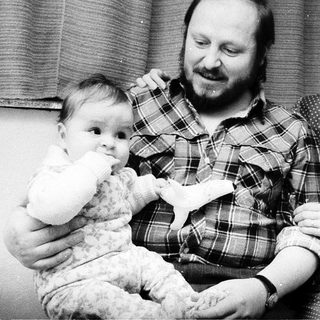 Family portrait with parents and baby near Christmas tree.