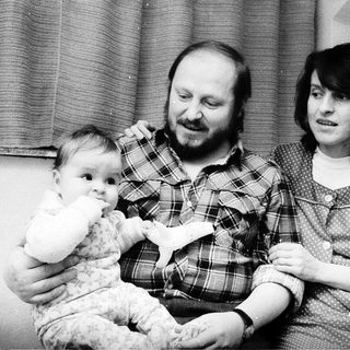 Family portrait with parents and baby near Christmas tree.