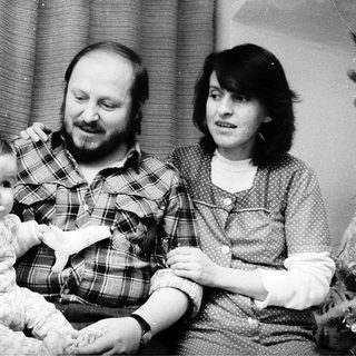 Family portrait with parents and baby near Christmas tree.