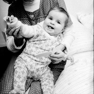 A woman plays with a smiling baby indoors.